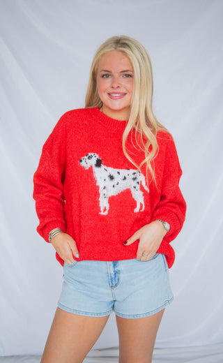 Woman wearing a red sweater with a dalmation dog design against a plain background