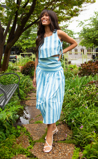 Woman in a blue and white striped outfit standing in a garden