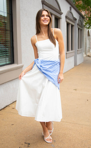 Women wearing a white maxi dress with a blue and white striped bandana wrapped around the waist. 