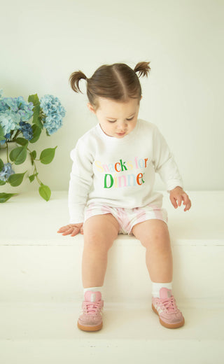 toddler wearing graphic sweatshirt that reads "snacks for dinner" in a colorful print 
