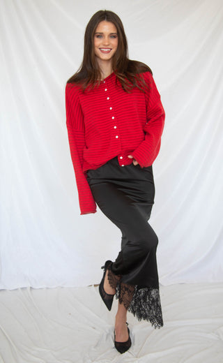 Woman wearing a red sweater and black lace trim skirt against a white background for valentine's day