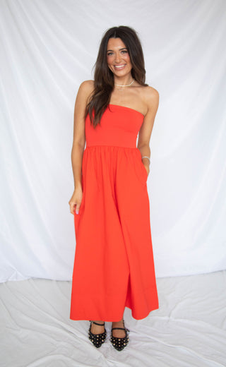 Woman wearing a red strapless dress against a white background