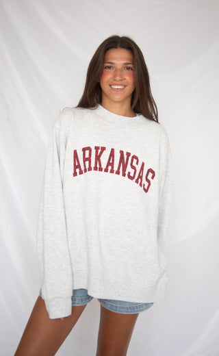 Person wearing a white sweatshirt with 'ARKANSAS' printed in red on a white background