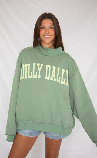 Woman wearing a green 'Dilly Dally' sweatshirt against a white background