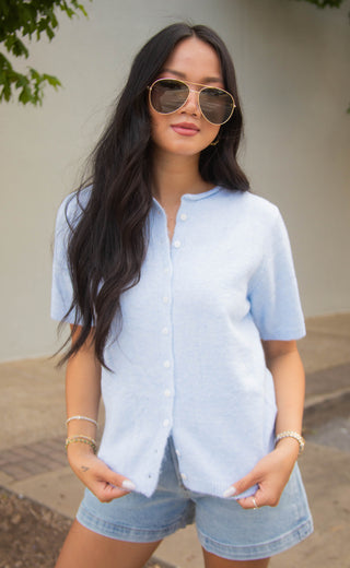 Woman wearing a light blue cardigan and denim shorts outdoors