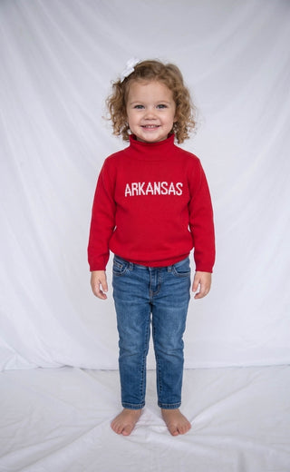 Child wearing a red 'ARKANSAS ' sweatshirt against a white background