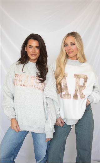 Two women wearing grey mock neck sweatshirts with camo ARKANSAS and AR text, standing against a plain background. 