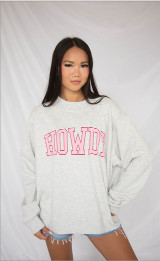 Person wearing a white sweatshirt with 'HOWDY' printed in pink on a plain background